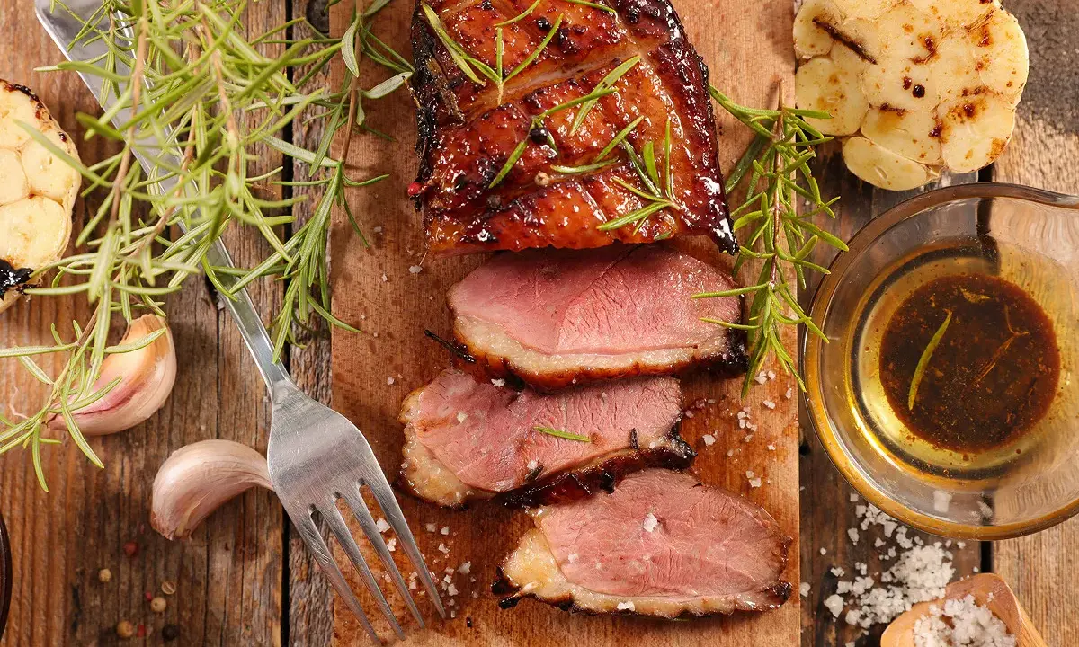Magret de canard tranché, servi avec une sauce pour magret de canard, romarin, ail rôti et gros sel.