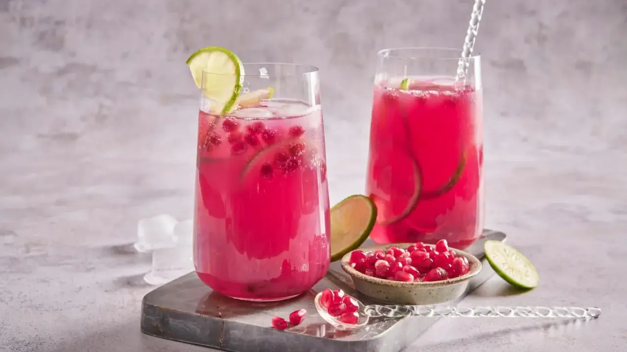 Cocktail fruité et rafraîchissant, ce cocktail fruit du dragon est garni de quartiers de citron vert et de graines de grenade.