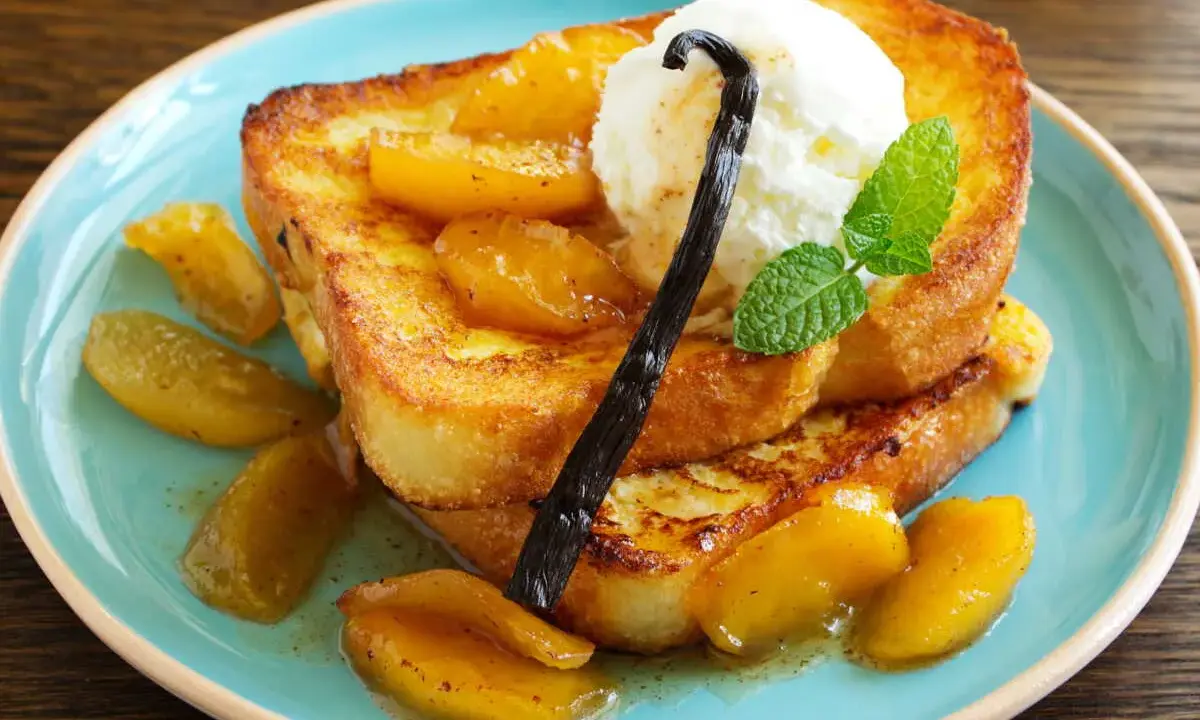 Délicieux pain perdu brioché, garni de fruits caramélisés, d'une boule de glace à la vanille et d'une gousse de vanille.