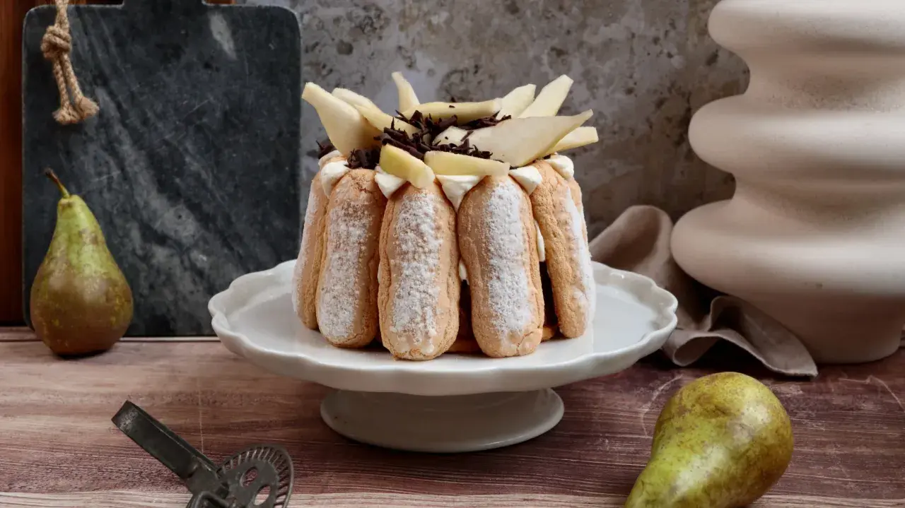 Charlotte poire chocolat, un dessert élégant avec des biscuits à la cuillère, garni de poires fraîches et de copeaux de chocolat.