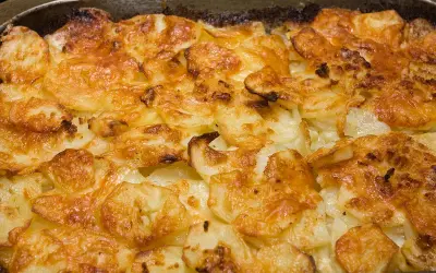 Un gratin dauphinois doré et croustillant, prêt à être dégusté. Les fines tranches de pommes de terre sont nappées d'une sauce crémeuse et gratinées à la perfection.