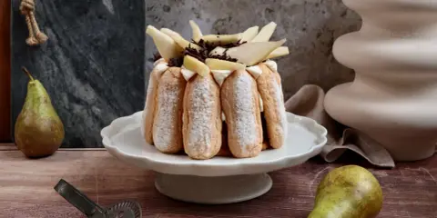 Charlotte poire chocolat, un dessert élégant avec des biscuits à la cuillère, garni de poires fraîches et de copeaux de chocolat.