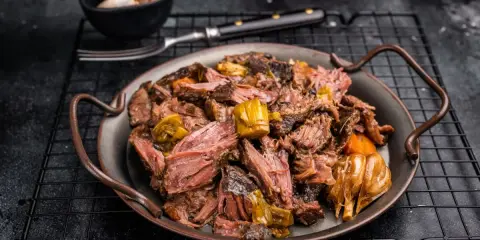 Joue de bœuf effilochée, tendre et savoureuse, servie avec des légumes fondants. Un délice pour les amateurs de viande.