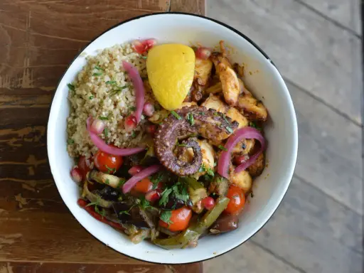 Un plat coloré avec du poulpe grillé, du quinoa, des légumes rôtis et une touche de citron. La marinade pour poulpe grillé a sublimé ce plat.