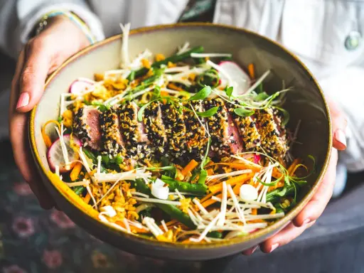Un délicieux tataki de thon, enrobé de sésame noir et blanc, repose sur un lit de légumes croquants : haricots verts, carottes râpées, radis et champignons enoki.