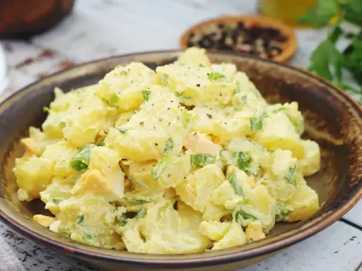 Salade de pomme de terre crémeuse avec des morceaux d'œufs durs et de ciboule, assaisonnée de poivre noir. Un plat réconfortant et savoureux.