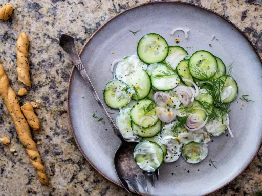 Salade de concombre crémeuse, parfaite pour une recette légère. Des rondelles fines de concombre, oignon rouge, aneth frais et une sauce onctueuse.