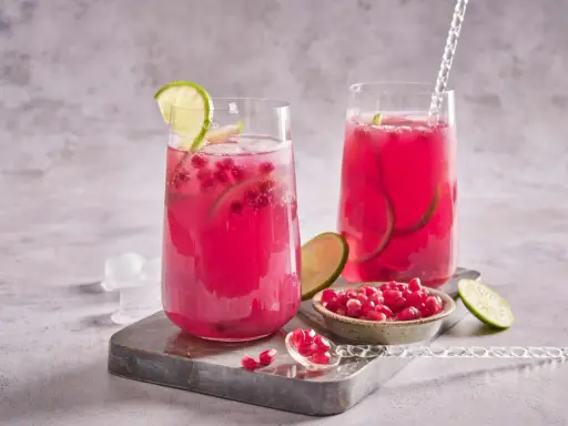 Cocktail fruité et rafraîchissant, ce cocktail fruit du dragon est garni de quartiers de citron vert et de graines de grenade.