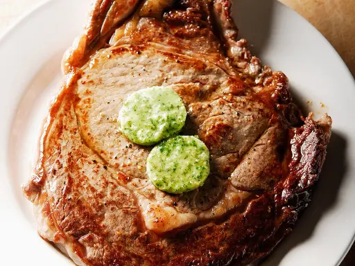 Un savoureux steak de bœuf, parfaitement grillé, est garni de deux rondelles de beurre maître d'hôtel, prêt à fondre.
