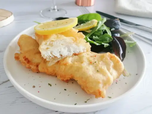 Poisson pané croustillant, servi avec une salade verte et des quartiers de citron. Un délice de fish and chips !