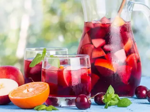 Une carafe et des verres de sangria rouge remplis de fruits frais, parfaits pour une recette de sangria rouge estivale.