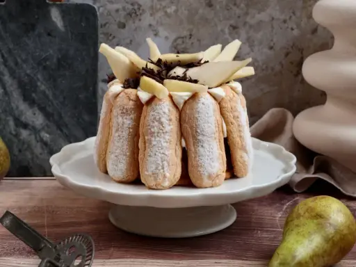 Charlotte poire chocolat, un dessert élégant avec des biscuits à la cuillère, garni de poires fraîches et de copeaux de chocolat.