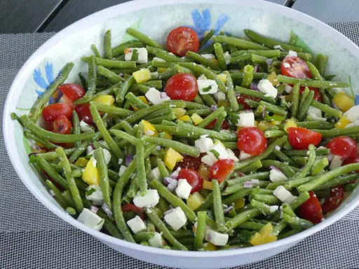 Salade estivale de haricots verts, tomates cerises, poivrons jaunes et feta. Un délice frais et coloré.