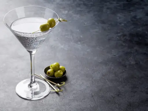 Un verre de dry martini, garni de deux olives, prêt à être dégusté. La recette parfaite pour un apéritif chic.