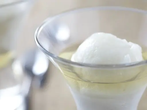 Une boule de sorbet citron dans un verre rempli de Calvados. Une recette de trou normand pour un dessert rafraîchissant.