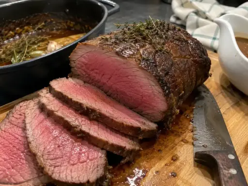 Un délicieux roti de boeuf cocotte, saignant et tendre, prêt à être dégusté avec sa sauce onctueuse.