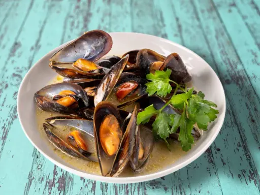 Un plat de moules au roquefort, garni de persil frais, baignant dans une sauce crémeuse.
