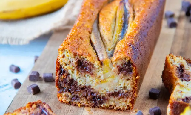 Un délicieux banana bread healthy, garni de pépites de chocolat, avec des bananes entières sur le dessus.