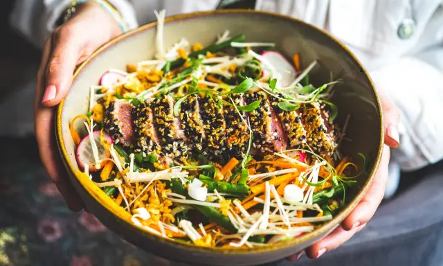 Un délicieux tataki de thon, enrobé de sésame noir et blanc, repose sur un lit de légumes croquants : haricots verts, carottes râpées, radis et champignons enoki.