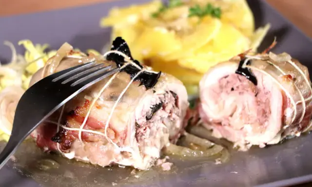 Une cuisse de poulet farcie, savoureusement roulée et ficelée, attend d'être dégustée avec une garniture de pommes de terre.