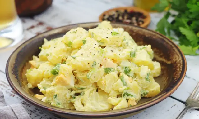 Salade de pomme de terre crémeuse avec des morceaux d'œufs durs et de ciboule, assaisonnée de poivre noir. Un plat réconfortant et savoureux.