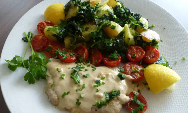 Escalope de veau crémeuse, accompagnée de pommes de terre sautées, tomates cerises rôties et quartiers de citron.