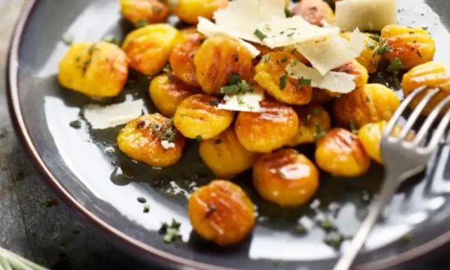 Gnocchis dorés à la sauce butternut, parsemés de copeaux de parmesan et d'herbes fraîches. Un délice réconfortant.