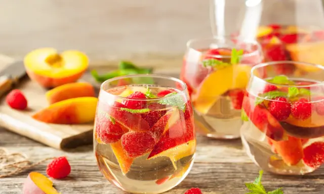 Délicieuse sangria blanche recette avec pêches, framboises et menthe fraîche. Parfait pour se rafraîchir !