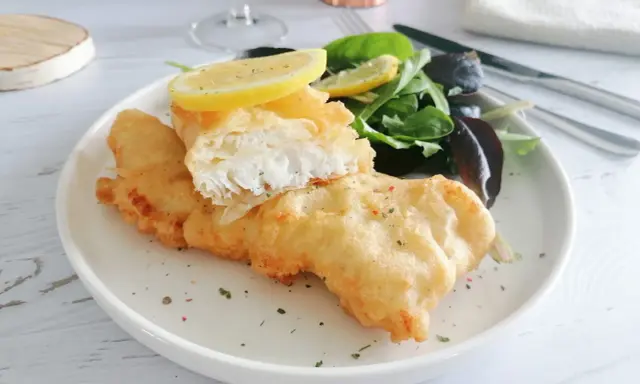 Poisson pané croustillant, servi avec une salade verte et des quartiers de citron. Un délice de fish and chips !