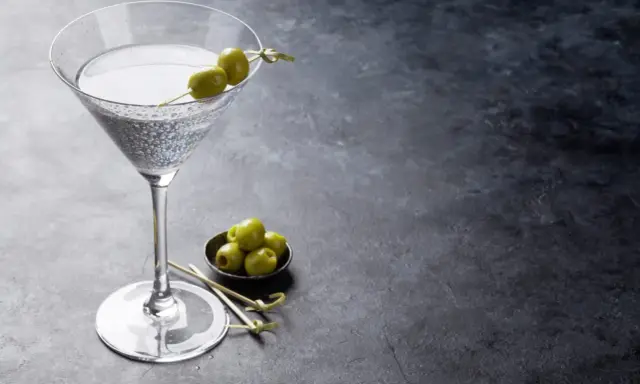 Un verre de dry martini, garni de deux olives, prêt à être dégusté. La recette parfaite pour un apéritif chic.