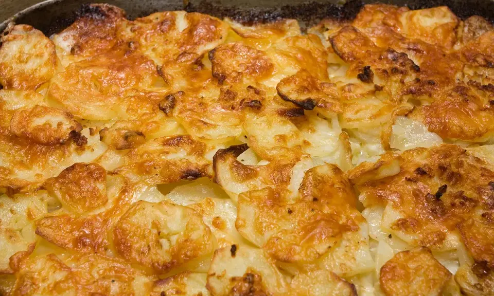 Un gratin dauphinois doré et croustillant, prêt à être dégusté. Les fines tranches de pommes de terre sont nappées d'une sauce crémeuse et gratinées à la perfection.