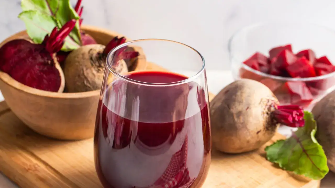 Verre de jus de betterave rouge vif, betteraves enti&egrave;res et coup&eacute;es en d&eacute;s &agrave; proximit&eacute;. Id&eacute;al pour savoir comment faire du jus de betterave.