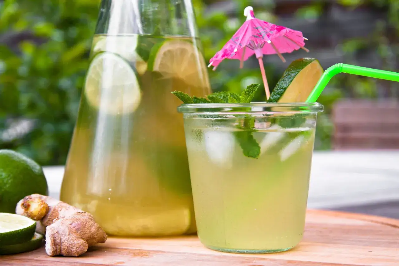 Une carafe et un verre remplis de th&eacute; glac&eacute; rafra&icirc;chissant avec des tranches de citron vert, de la menthe et du gingembre. Parfait pour une recette de th&eacute; glac&eacute; maison.