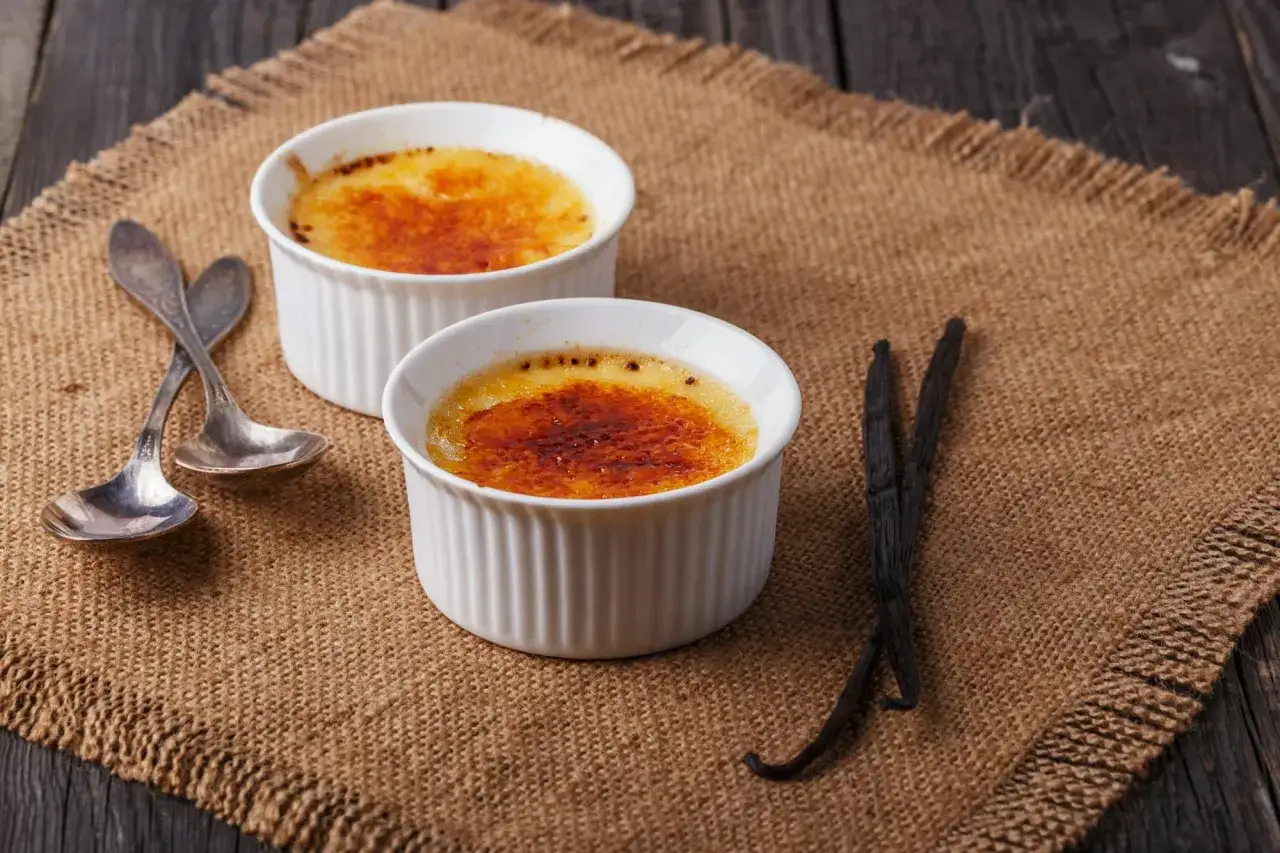 Deux cr&egrave;mes br&ucirc;l&eacute;es &agrave; la vanille, pr&ecirc;tes &agrave; &ecirc;tre d&eacute;gust&eacute;es. La cro&ucirc;te caram&eacute;lis&eacute;e craque sous la cuill&egrave;re.