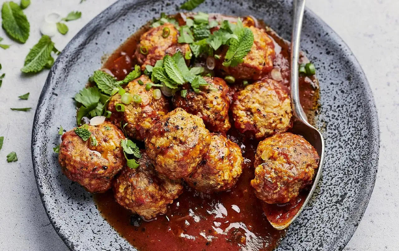 Boulettes de viande savoureuses baignant dans une sauce rouge app&eacute;tissante, garnies de menthe fra&icirc;che. La meilleure sauce pour boulette de viande, c'est celle-ci !