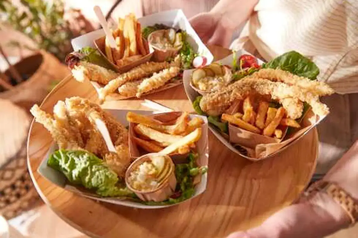 Trois portions de fish and chips, avec frites croustillantes et poisson pan&eacute;, accompagn&eacute;es de salade et de sauce tartare.